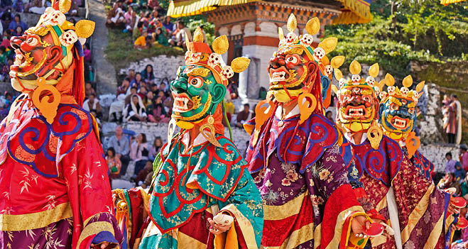 T nzer in bunten Gew ndern und Masken mit Fratzen und Kronen bei traditionellem Fest vor Publikum. 