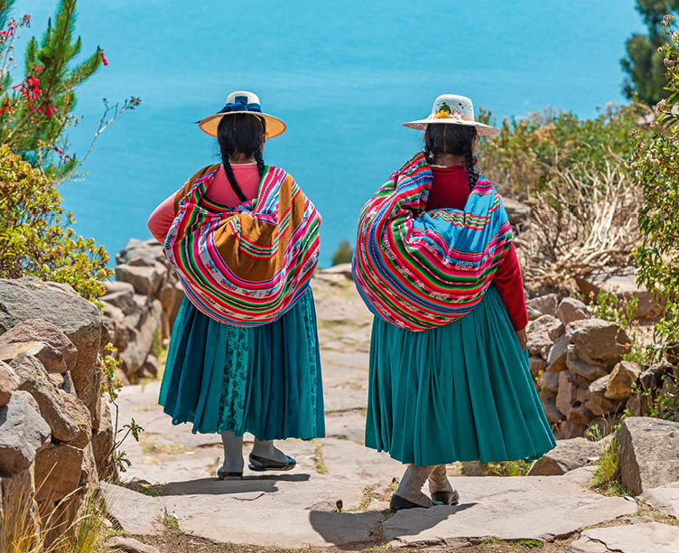 Zwei Frauen in traditioneller Kleidung mit bunten T chern und Blick auf den Titicacasee.