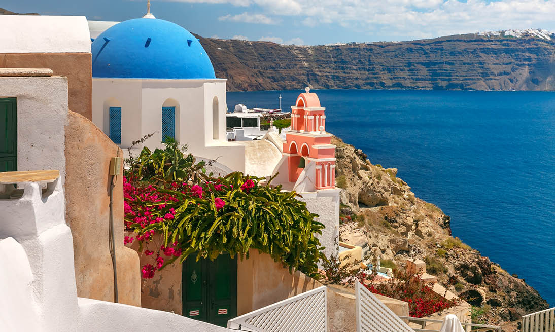 Picturesque view of white houses and church with blue domes in Oia or Ia, island Santorini, Greece