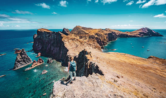 Description: Athletic woman enjoys the view on rocky cliff from a steep cliff. S o Louren o, Madeira Island, Portugal, Europe.