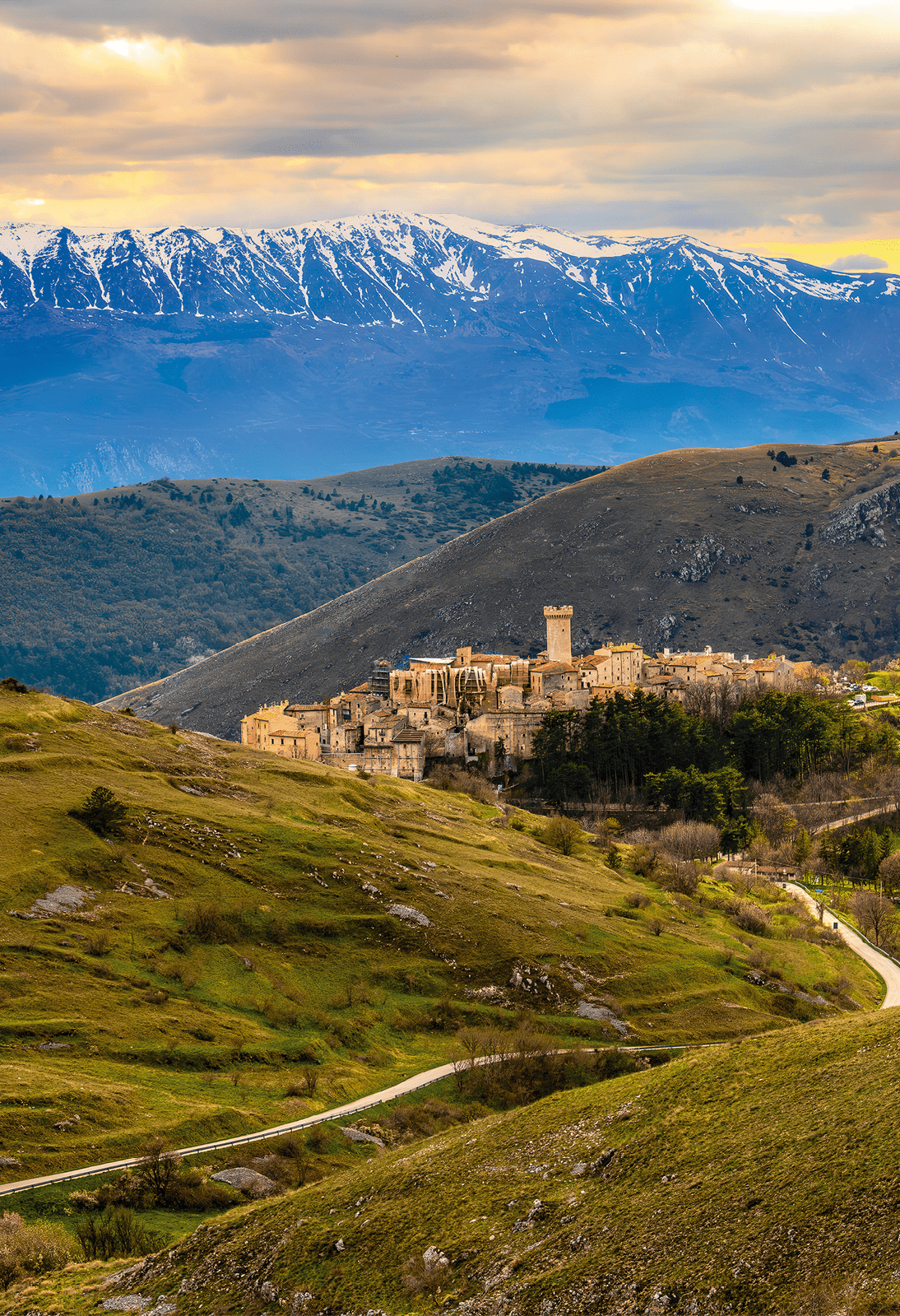 Historisches Dorf auf einem H gel, umgeben von gr nen T lern, im Hintergrund schneebedeckte Bergkette.