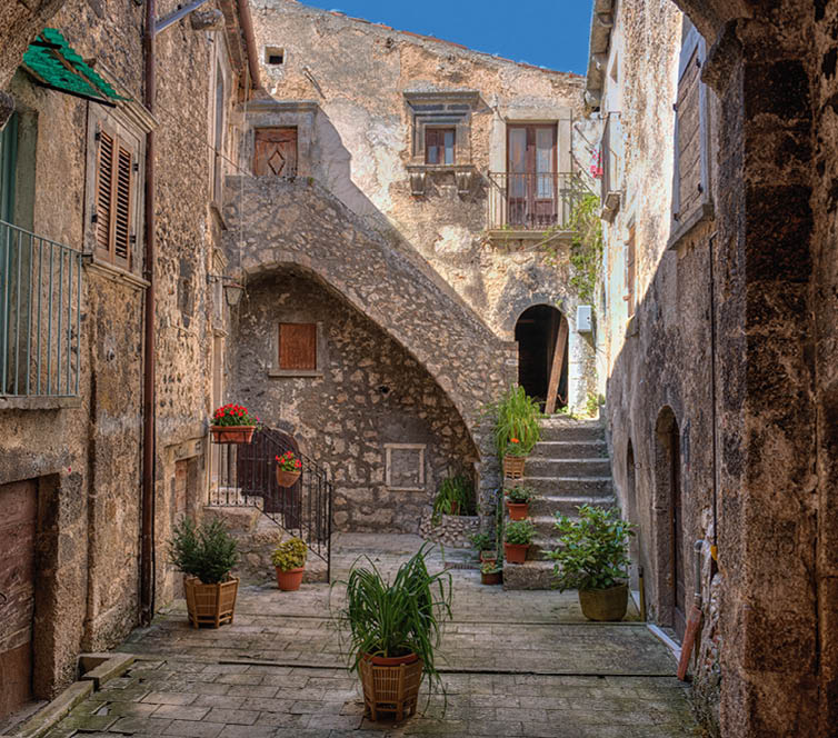 Enge, gepflasterte Gasse mit alten Steinh usern, Au entreppen und vielen Topfpflanzen.