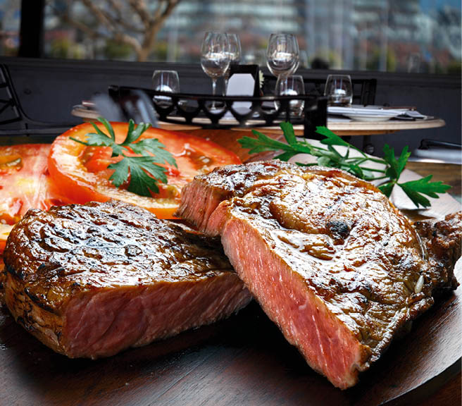 Saftiges, perfekt gebratenes Steak auf einem Teller, begleitet von Tomatenscheiben und Petersiliengarnitur in einem stilvollen Restaurantambiente.