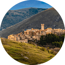 Historisches Dorf auf einem H gel, umgeben von gr nen T lern, im Hintergrund schneebedeckte Bergkette.