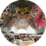 Blick in die Markthalle mit zentralem Verkaufsstand und bunt gestalteter Decke.