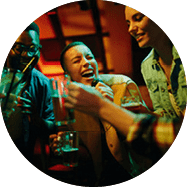 Gruppe junger Menschen trinkt und lacht gemeinsam in einer Bar bei farbigem Licht.