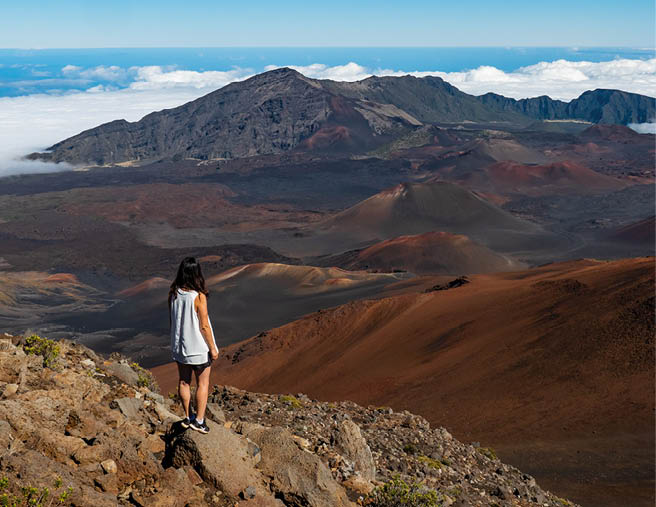 Man in White T-shirt and Blue Shorts Standing on Brown Rock Mountain
