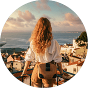 A young female tourist standing on a platform surrounded by fences and observing Lisbon at daytime in Portugal