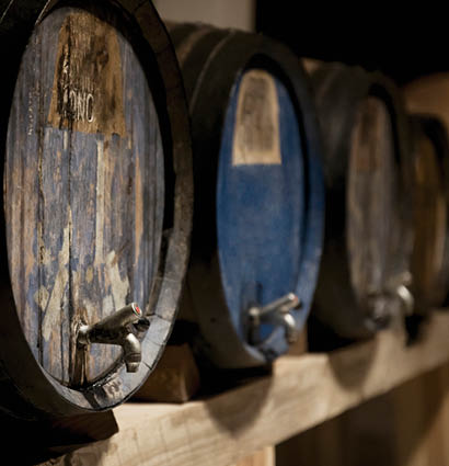 Alte Holzf sser mit Zapfh hnen in einem Weinkeller auf Holzregalen